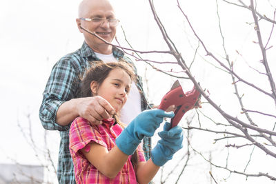 Portrait of smiling young woman standing against bare tree