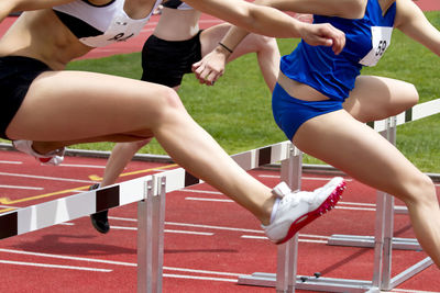 Low section of female athletes crossing hurdles