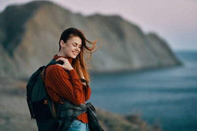 Young woman standing against sea