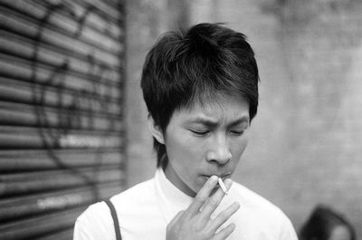 Close-up of man smoking against wall