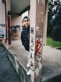 Portrait of young woman standing on graffiti