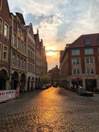 Street amidst buildings in city during sunset