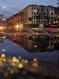 Reflection of illuminated buildings in puddle at night