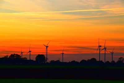 Silhouette of wind turbines on green field during sunset