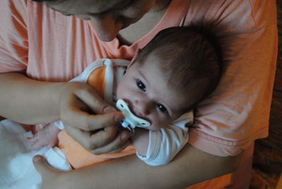 Mother placing pacifier in toddler son mouth