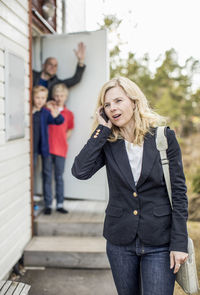 Woman using mobile phone with family in background