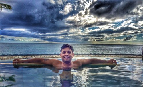 Portrait of shirtless man in swimming pool against sea