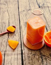 High angle view of orange juice in glass container on table