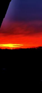 Silhouette landscape against dramatic sky during sunset