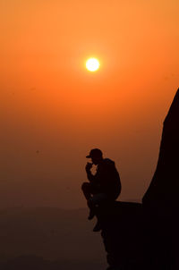 Silhouette man against orange sky during sunset