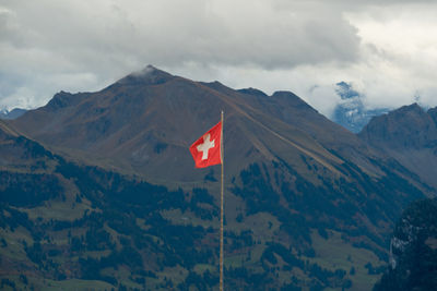 Swiss flag blowing in the wind. in the background you can see mountains