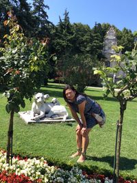 Portrait of smiling woman standing by sculpture at park