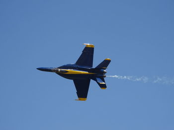 Low angle view of airplane flying against clear blue sky