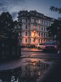 Wet street by buildings in city during rainy season