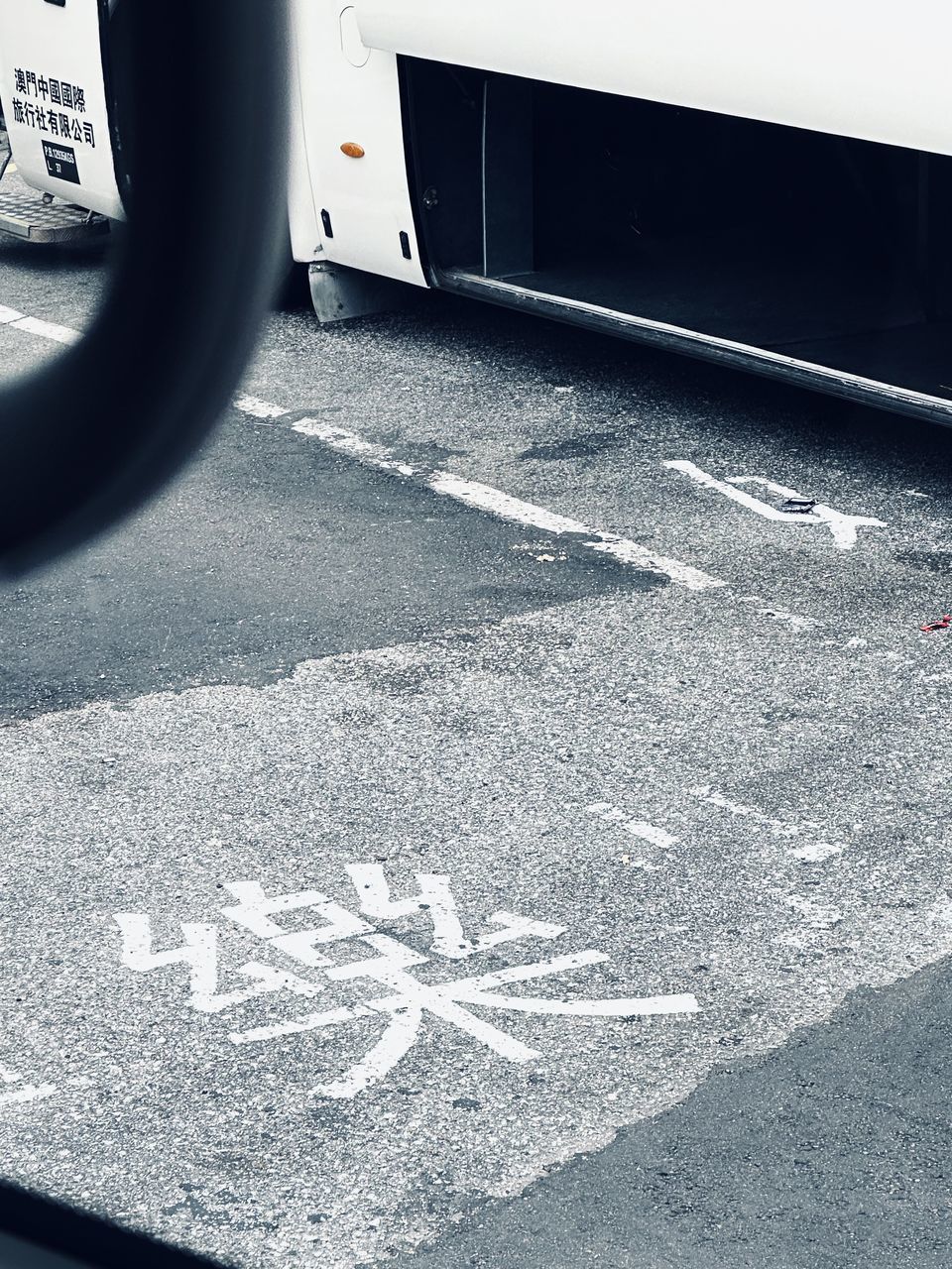 transportation, road, sign, white, asphalt, black, symbol, communication, city, mode of transportation, no people, vehicle, tarmac, day, street, road marking, tire, marking, text, road sign, road surface, land vehicle, motor vehicle, outdoors, western script, wheel