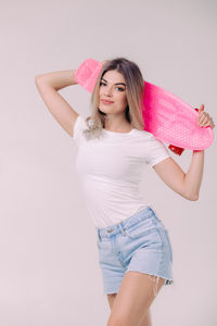 Portrait of young woman standing against white background