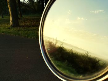 View of landscape seen through side-view mirror