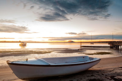 Omokoroa beach at sunrise. small boat parked on the sand. small pier. 