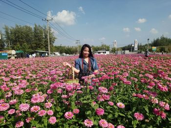 Portrait of smiling woman standing amidst flowering plants