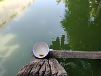 Close-up of coffee cup on wood against lake