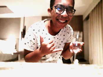 Portrait of smiling young man holding eyeglasses at home