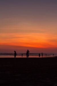 Silhouette people on beach against sky during sunset