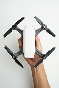 Cropped hand of woman holding drone against white background