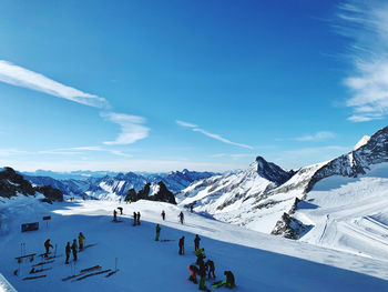 People skiing on snowcapped mountain against sky