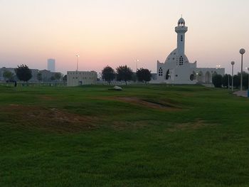 Buildings on field against sky during sunset