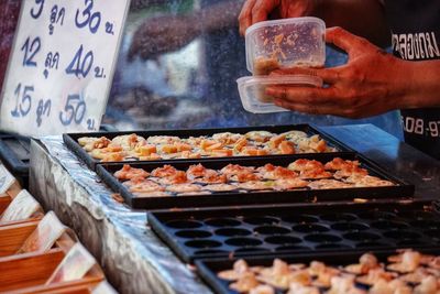 Midsection of person preparing food at market stall