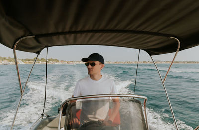 A young guy controls a boat on the sea.