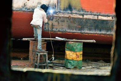 Rear view of man working at shipyard