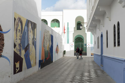 Rear view of people walking on street amidst buildings in city