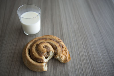 Glass of milk and eaten sweet bun on table