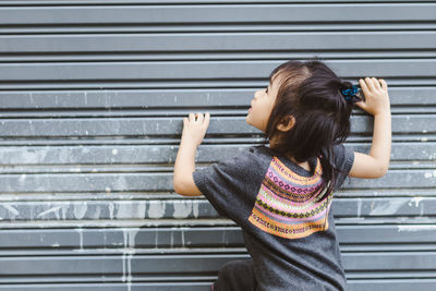 Rear view of girl playing by closed shutter
