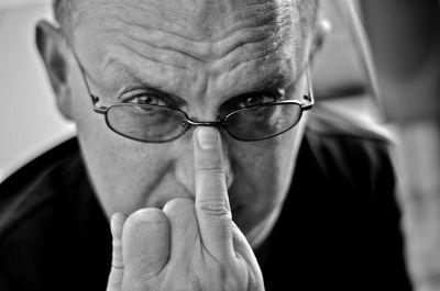 Close-up portrait of angry man adjusting eyeglasses