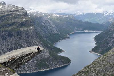 Woman sitting on cliff over lake 