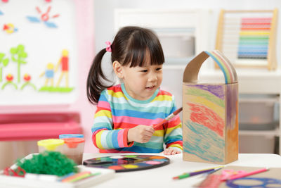 Young girl painting bird house craft at home 