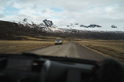 Cars on road against sky seen through car windshield