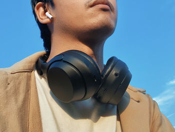 Midsection of man wearing headphones against sky