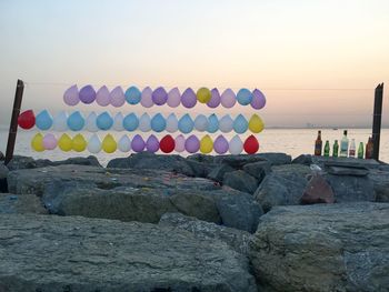 Multi colored rocks by sea against clear sky during sunset