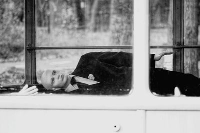 Portrait of woman lying on window