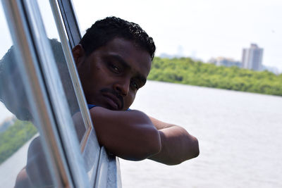 Portrait of mid adult man leaning on boat window at lake