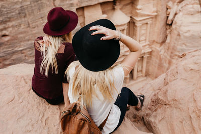 Rear view of friends sitting on rock formation