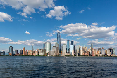 Sea by modern buildings against sky in city