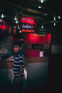 Boy standing in illuminated building