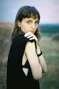 Side view portrait of young woman standing on field