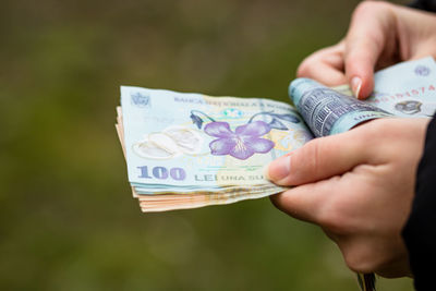 Close-up of hand holding paper against blurred background
