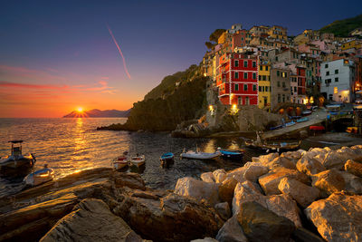 Riomaggiore by sea against sky during sunset