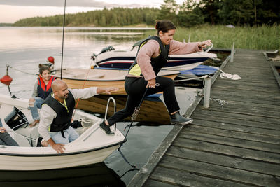 Family looking at woman jumping on pier from boat during summer